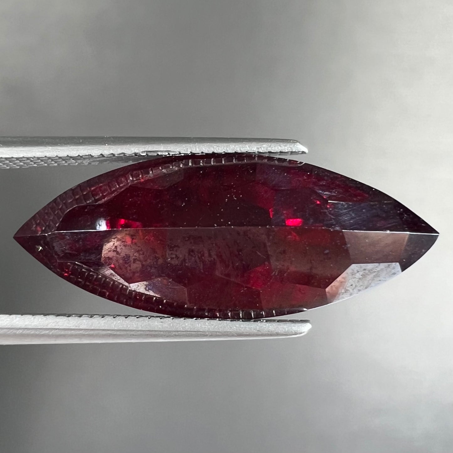 A loose, marquise cut cuprite gemstone.  The stone is a deep, crimson red color.