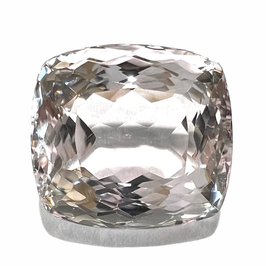 A loose, cushion cut morganite gemstone.  The stone is a light pink color.