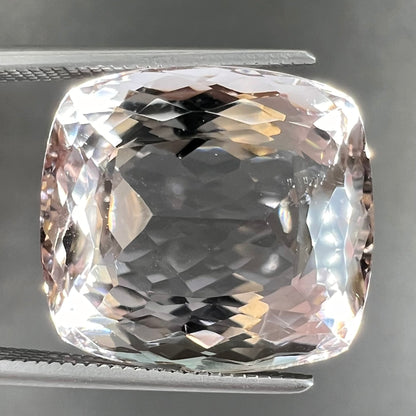 A loose, cushion cut morganite gemstone.  The stone is a light pink color.