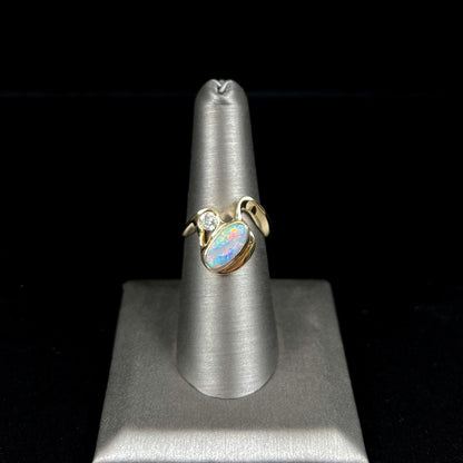 A ladies' yellow gold, bezel set ring mounted with a natural 1.15 carat black opal and round diamond.