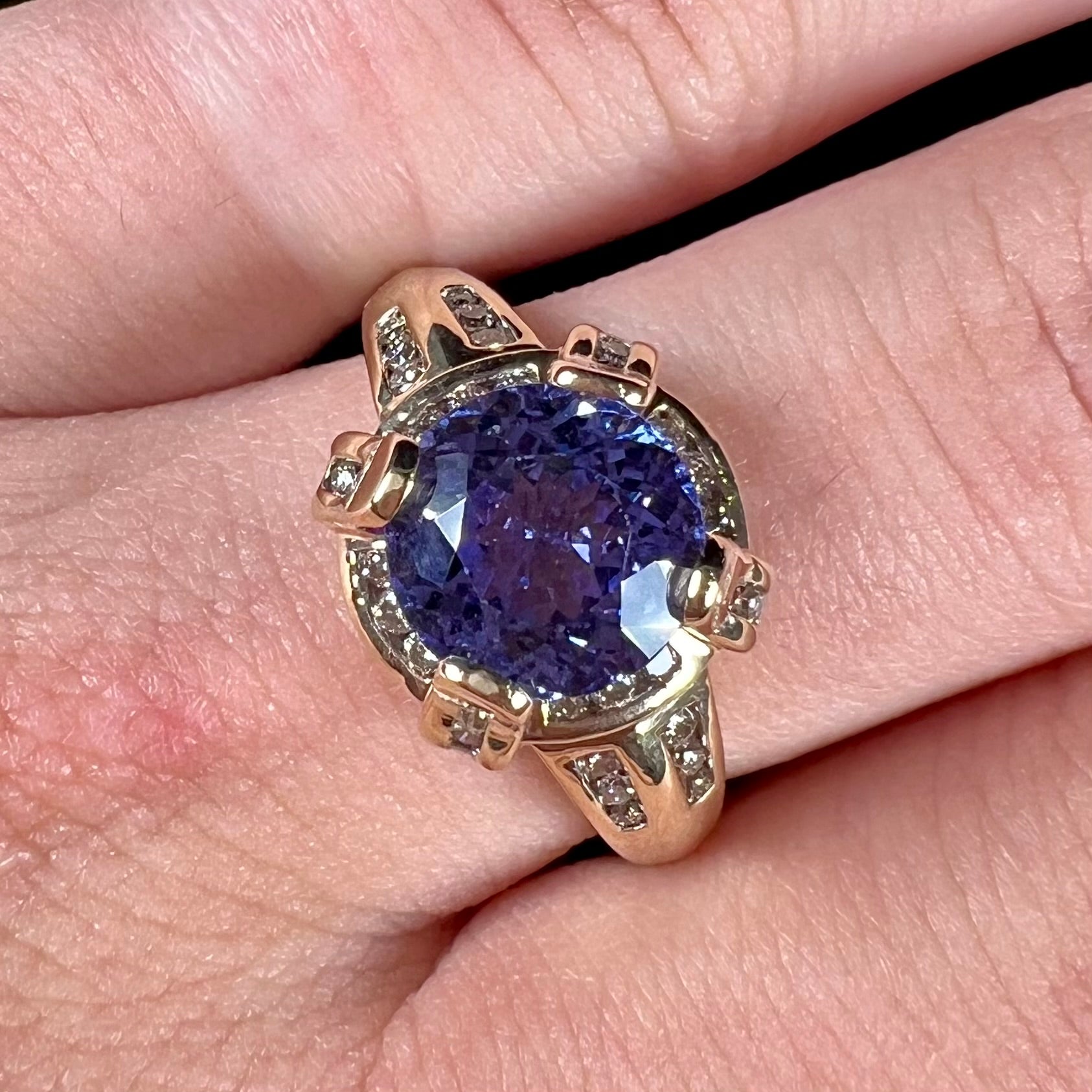 A ladies' yellow gold natural tanzanite and diamond ring.  Diamonds are channel set along the shank and in the prongs.