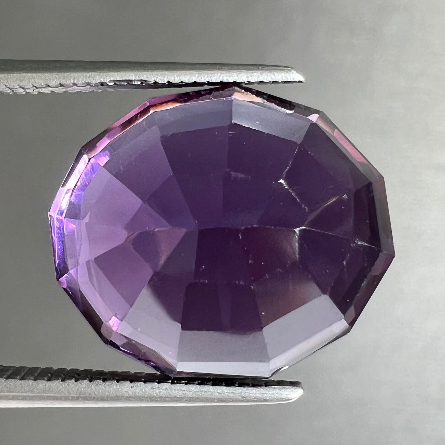 A loose, modified oval cut purple amethyst gemstone.
