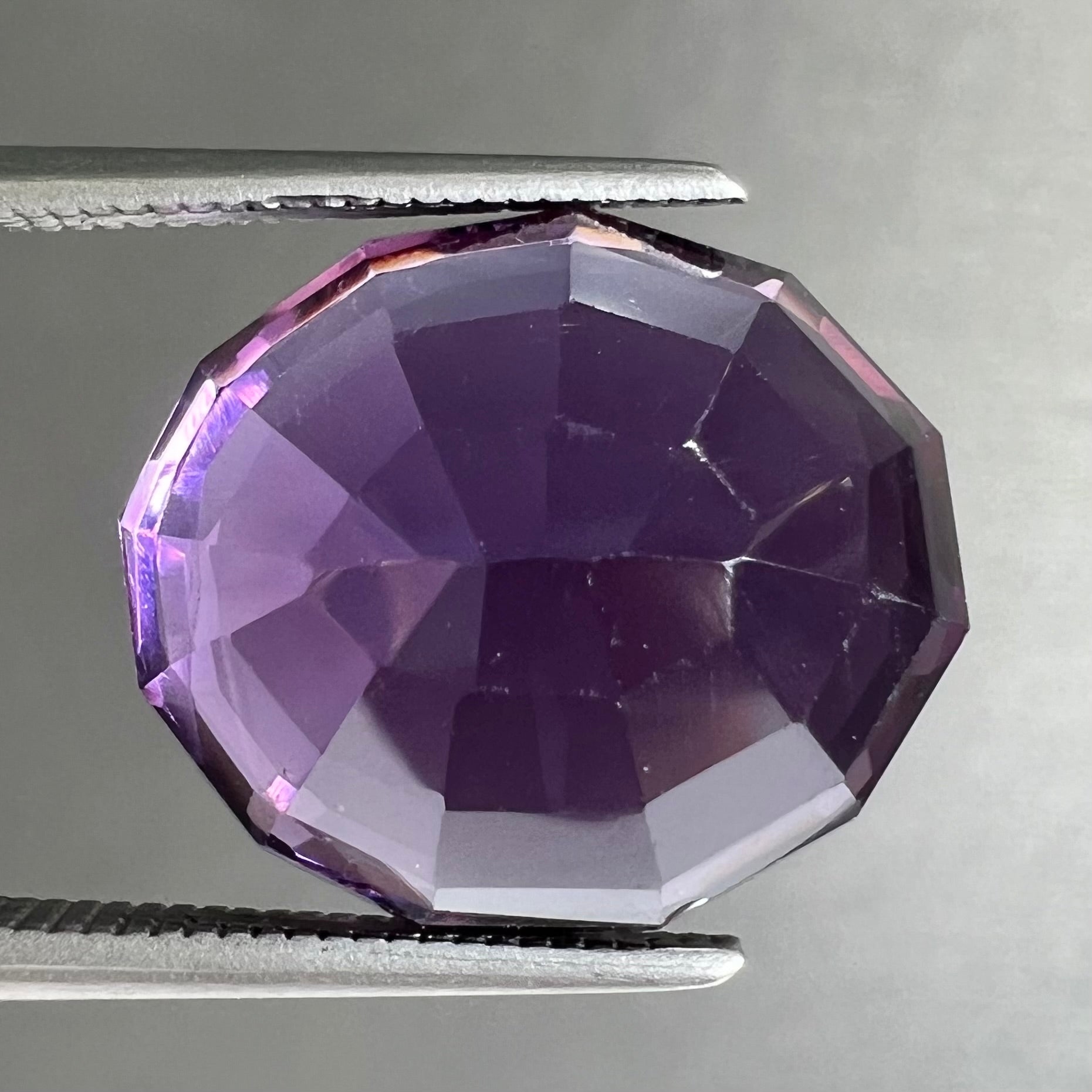 A loose, modified oval cut purple amethyst gemstone.