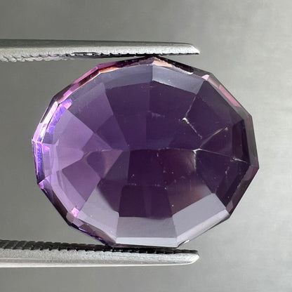 A loose, modified oval cut purple amethyst gemstone.