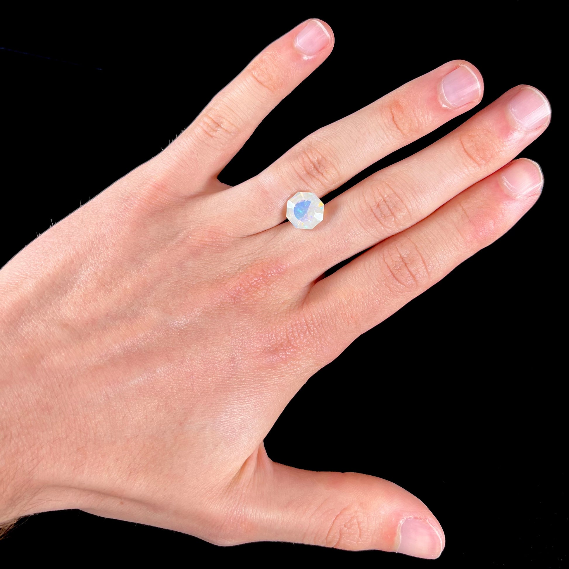 A loose, faceted octagon cut Mexican fire opal gemstone.  The stone is a light yellow color with blue and green fire.