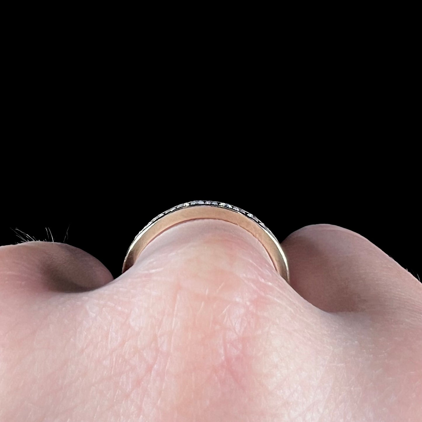 A unisex, thin yellow gold wedding band channel set with 12 round cut diamonds.