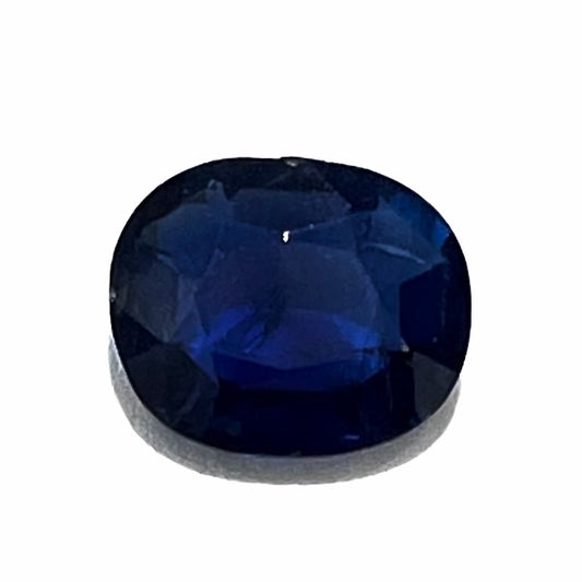 A loose, faceted oval cut dark blue natural sapphire stone.