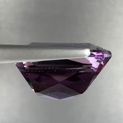 A loose, modified radiant cut amethyst stone.