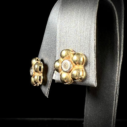 A pair of two-tone yellow and white gold diamond flower earrings.  The flower petals are yellow gold, and the diamonds are set in white gold bezels.
