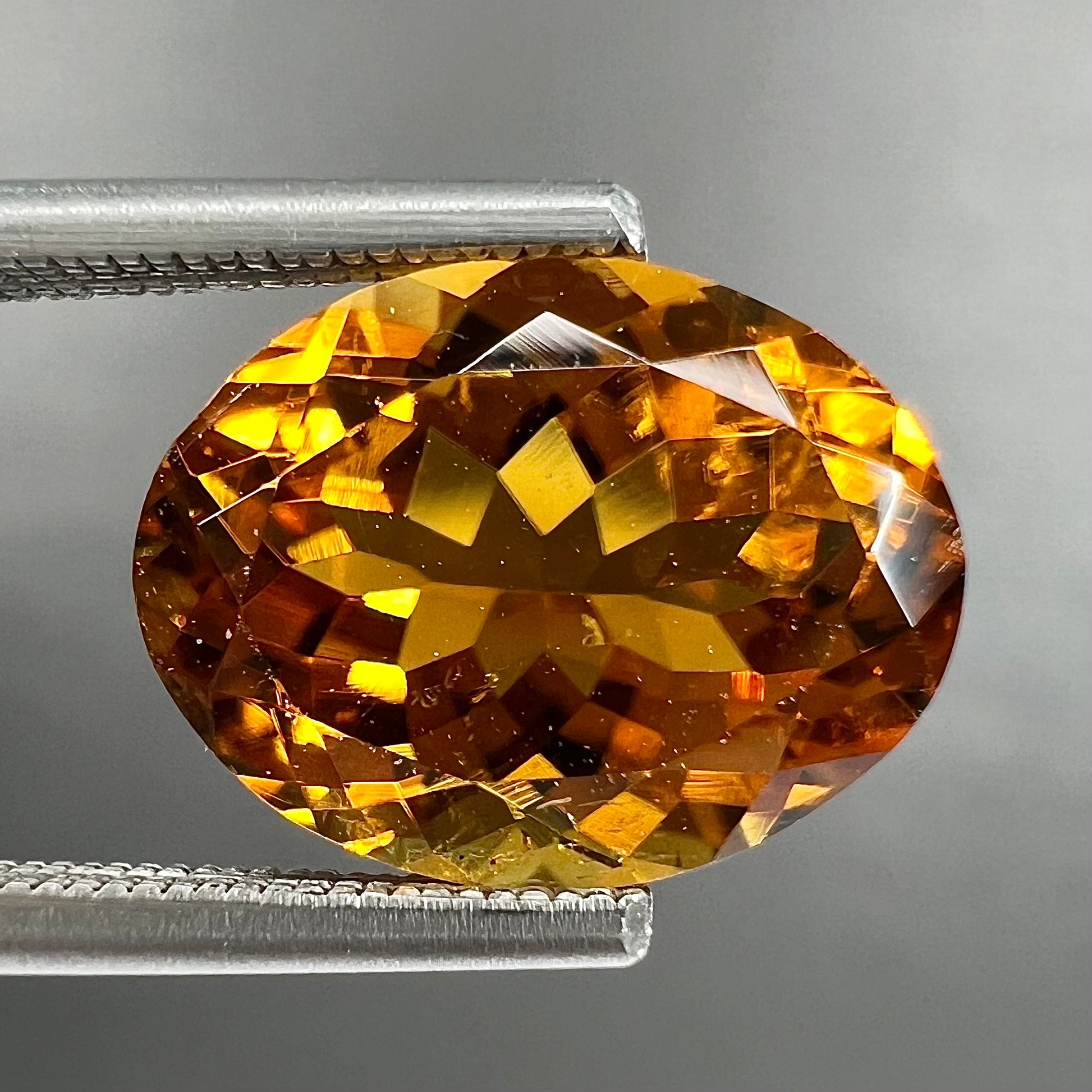 A loose, faceted oval cut orange dravite tourmaline gemstone.