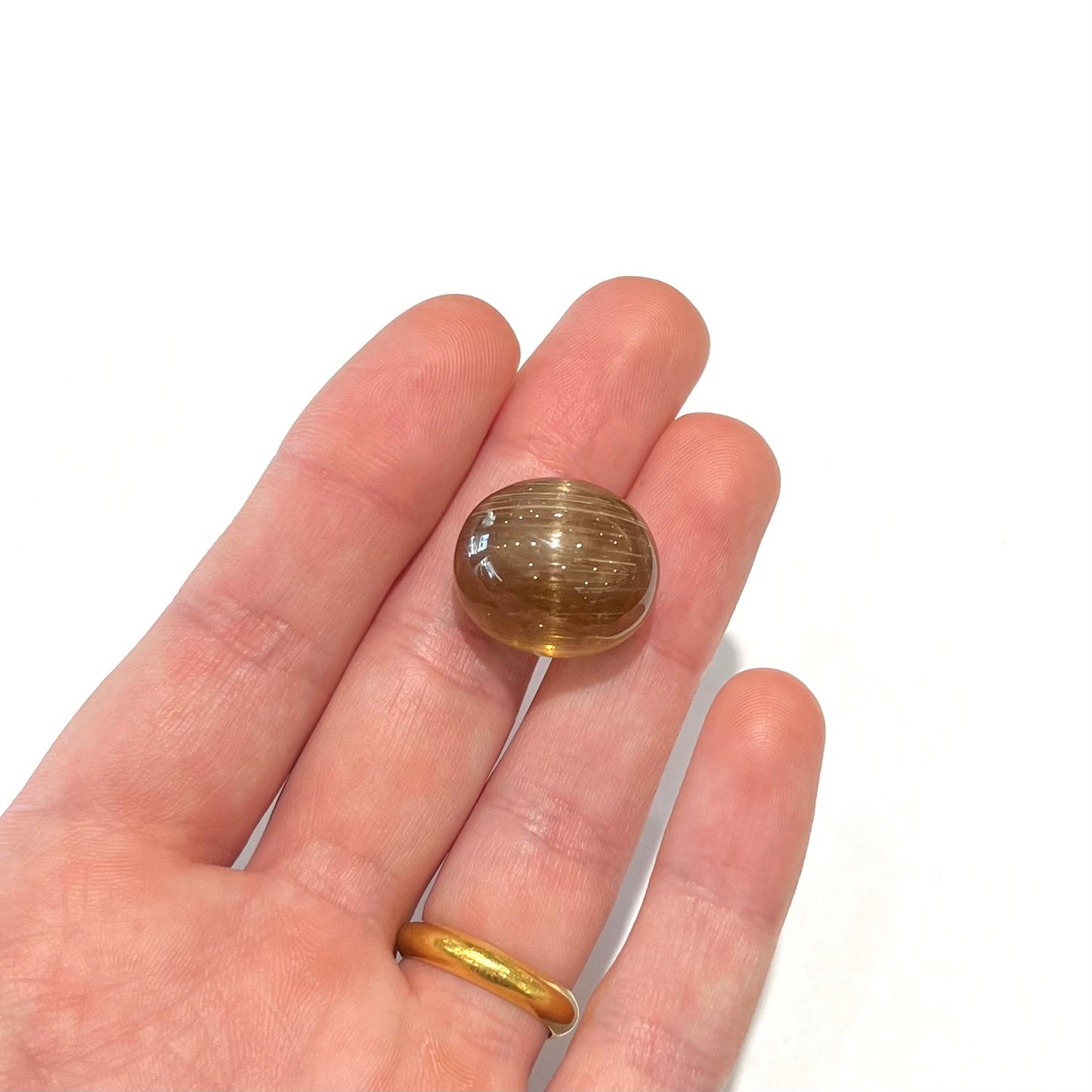 A loose, golden brown cat's eye dravite tourmaline gemstone.  The stone is cut into an oval shaped cabochon.