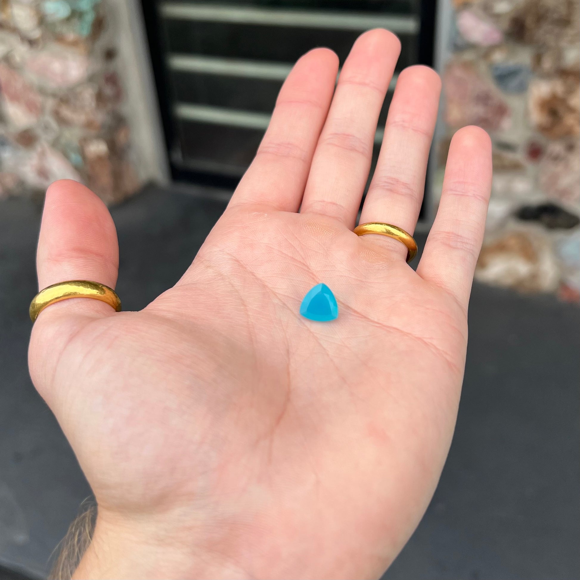 A loose, blue, trillion cut Paraiba chalcedony gemstone.