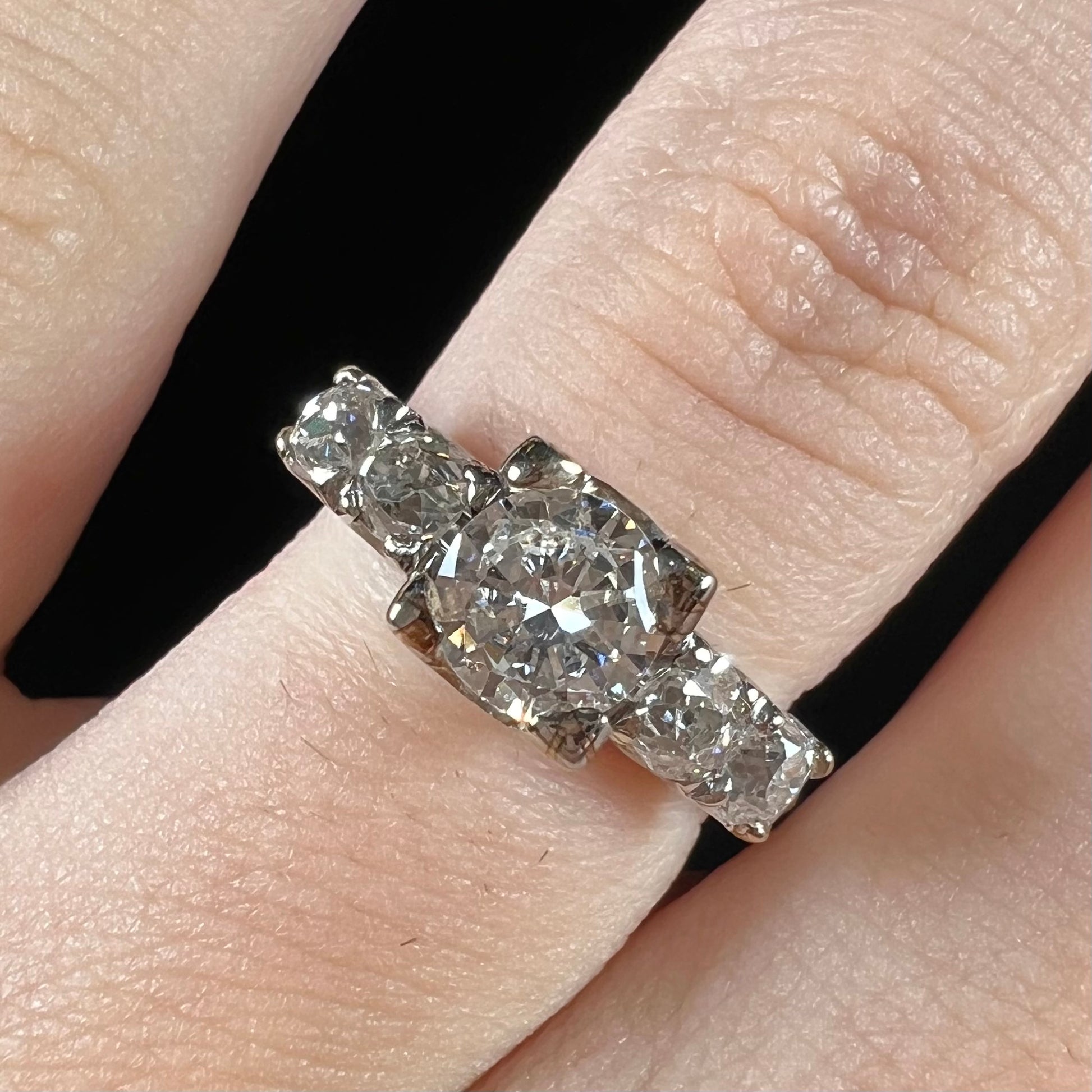 A ladies' 1800's antique white gold diamond ring.  The center stone is an Early American Cut diamond, and the accent stones are Old Mine Cut diamonds.