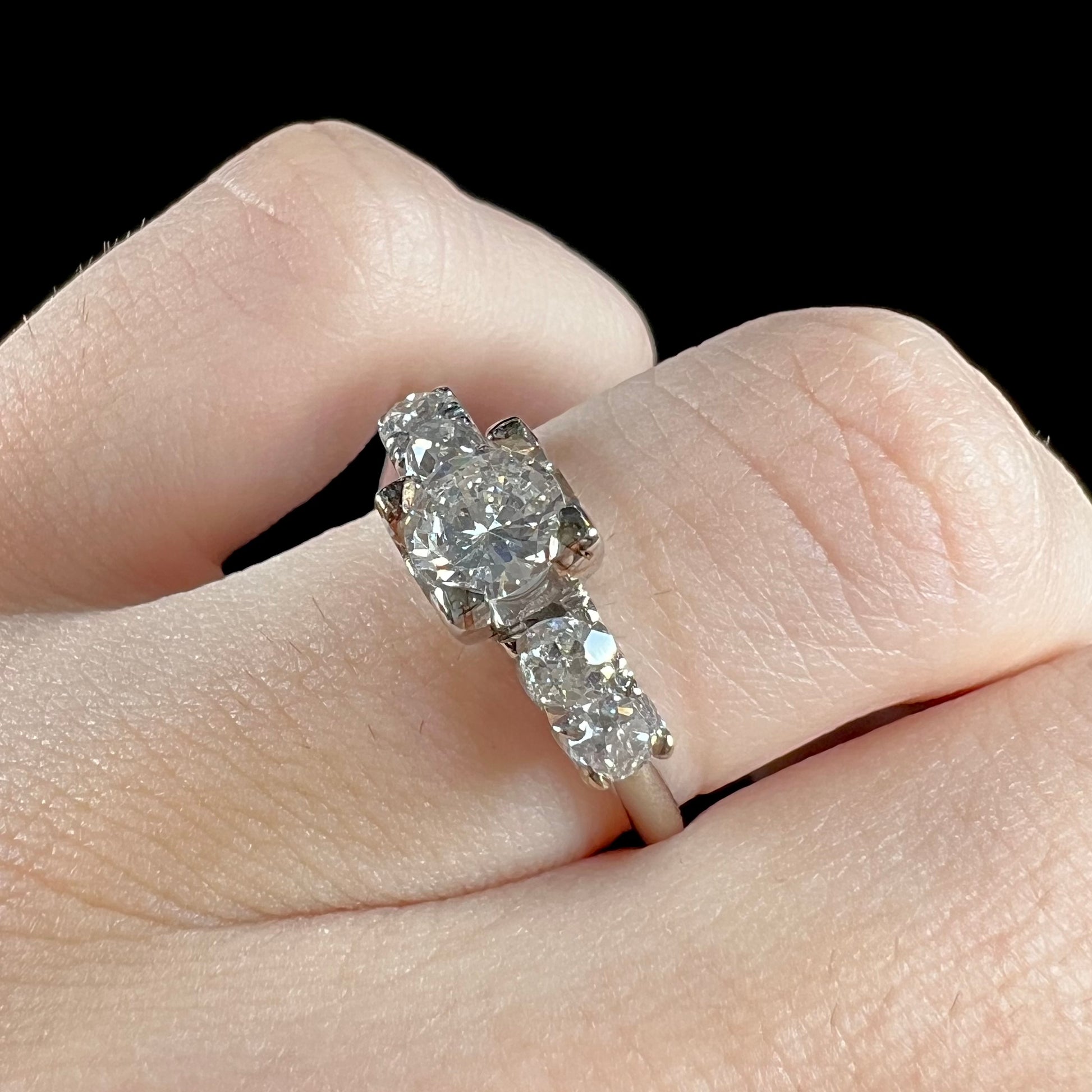 A ladies' 1800's antique white gold diamond ring.  The center stone is an Early American Cut diamond, and the accent stones are Old Mine Cut diamonds.