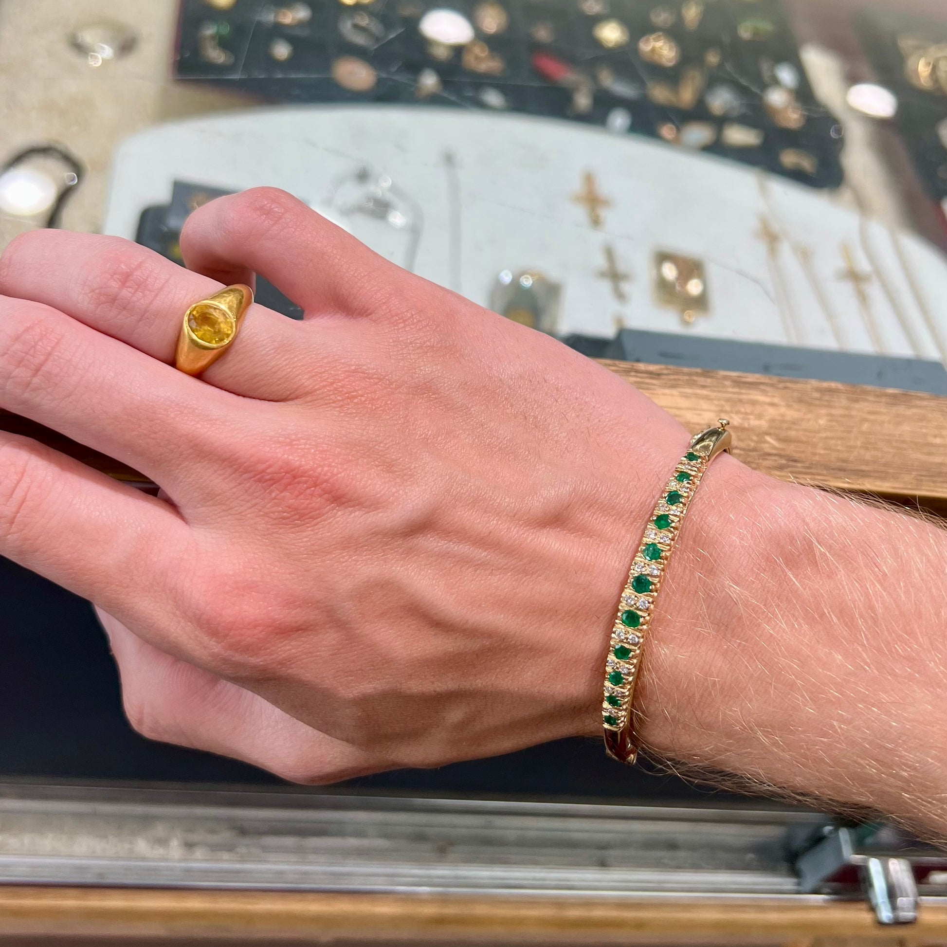 A ladies' yellow gold bangle bracelet set with round cut emeralds and diamonds.