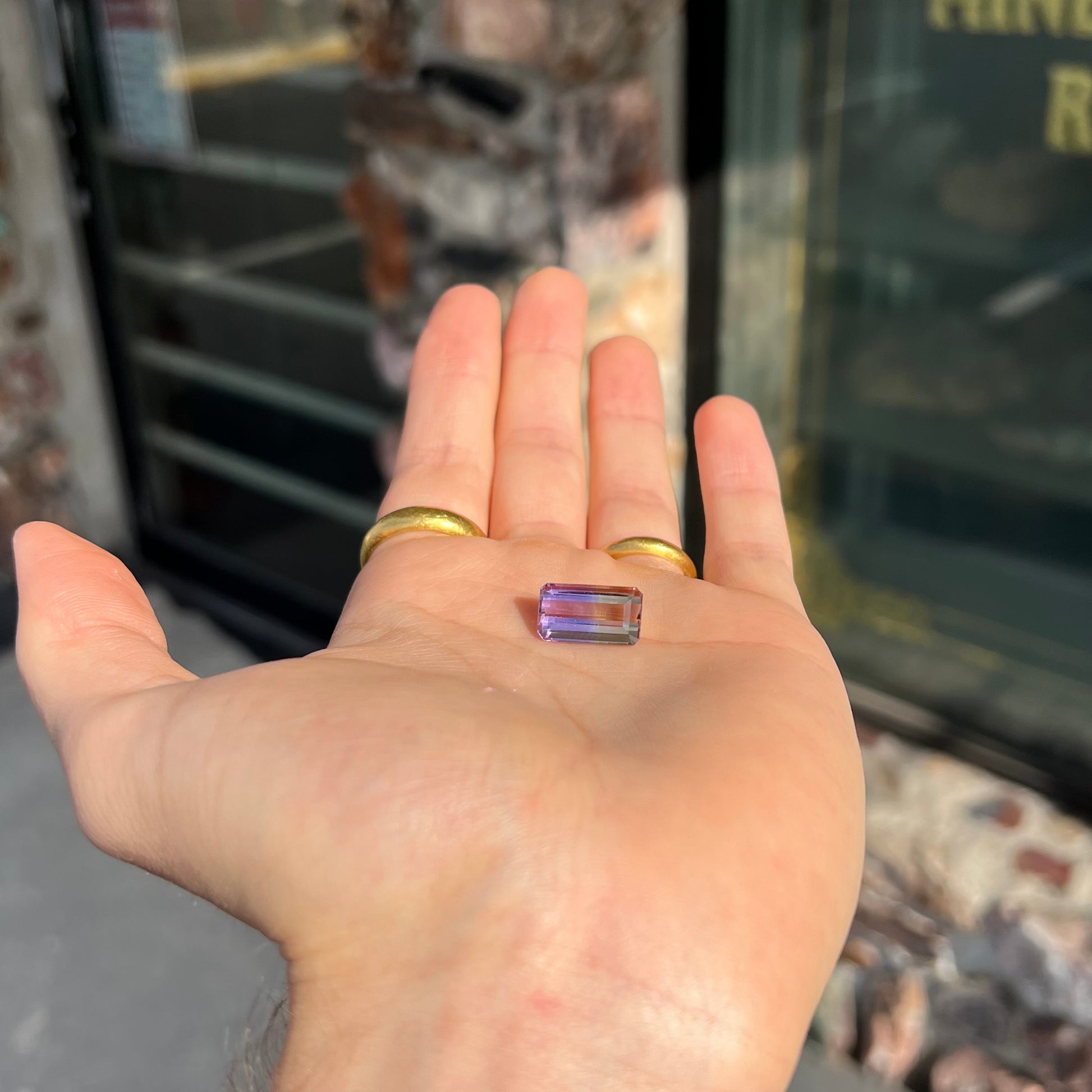 A loose, emerald cut ametrine stone.  The color fades from light purple to light yellow.