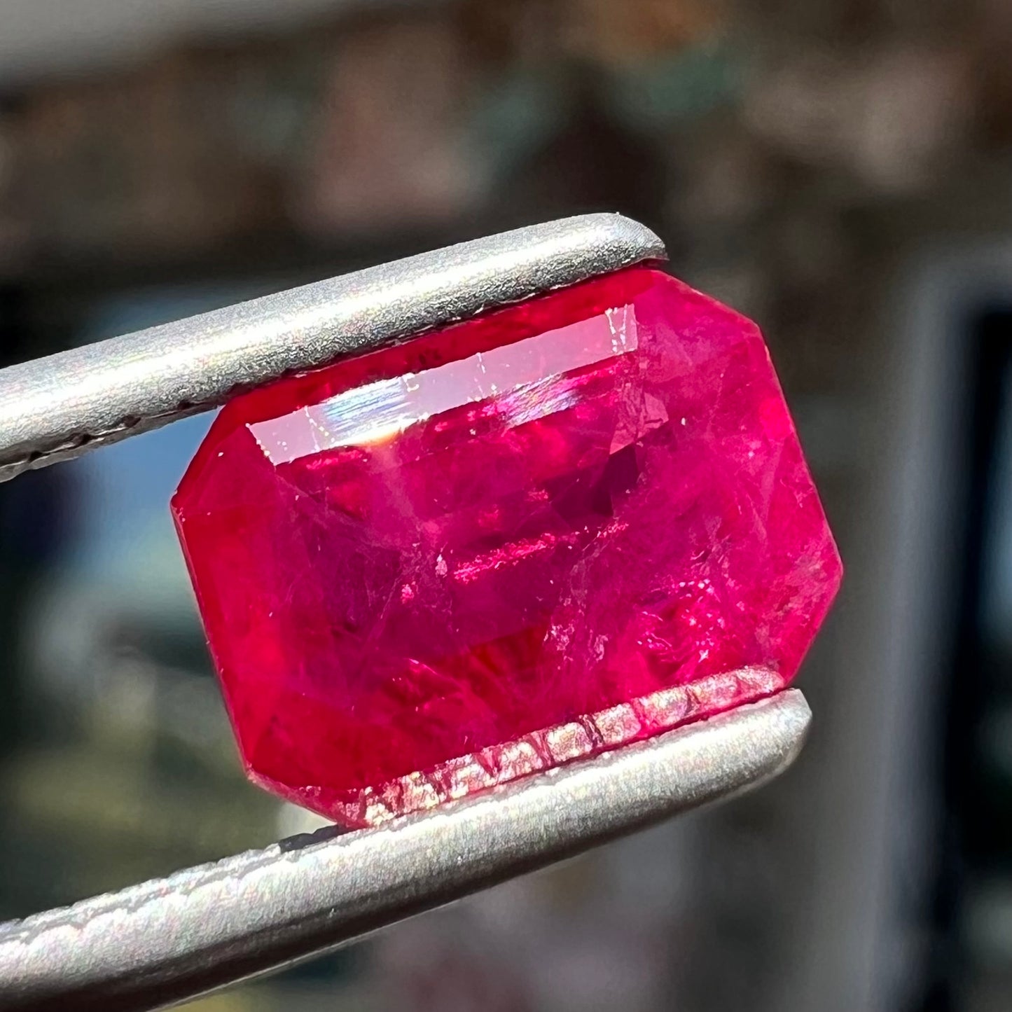 An emerald cut Burma ruby gemstone.  The stone is loose and a pinkish red color.