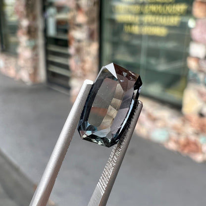 A loose, modified emerald cut, natural color change sapphire stone.  The stone shifts from black to blue to purple to green.