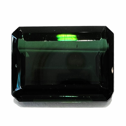 A faceted emerald cut dark green tourmaline gemstone.