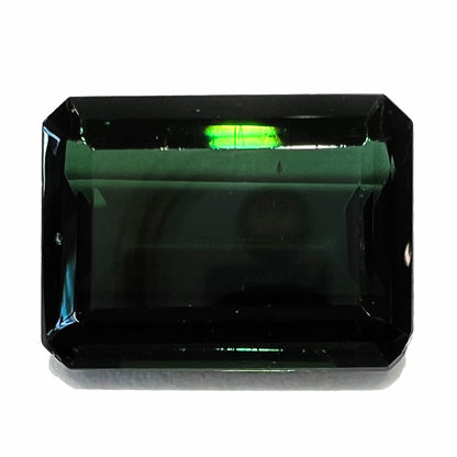 A faceted emerald cut dark green tourmaline gemstone.