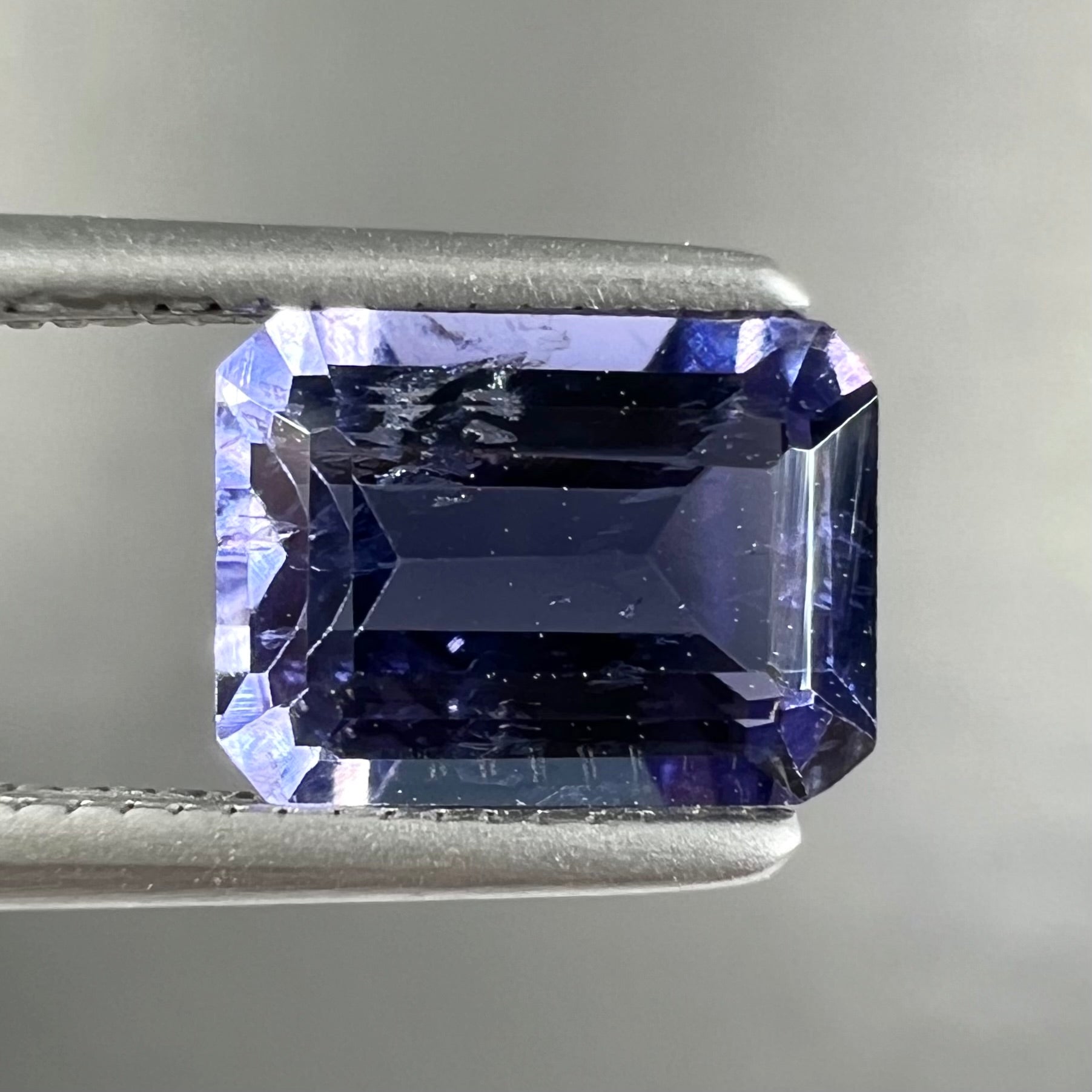 A loose, emerald cut blue iolite gemstone.