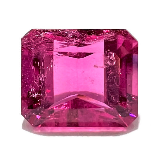 A loose, faceted modified emerald cut hot pink tourmaline stone.