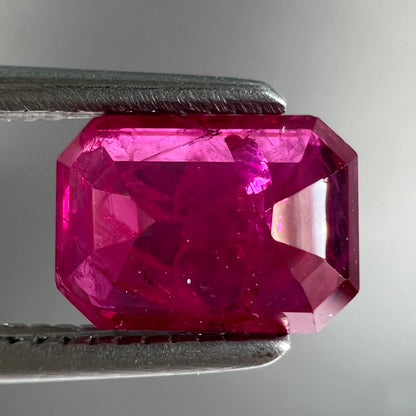 An emerald cut Burma ruby gemstone.  The stone is loose and a pinkish red color.