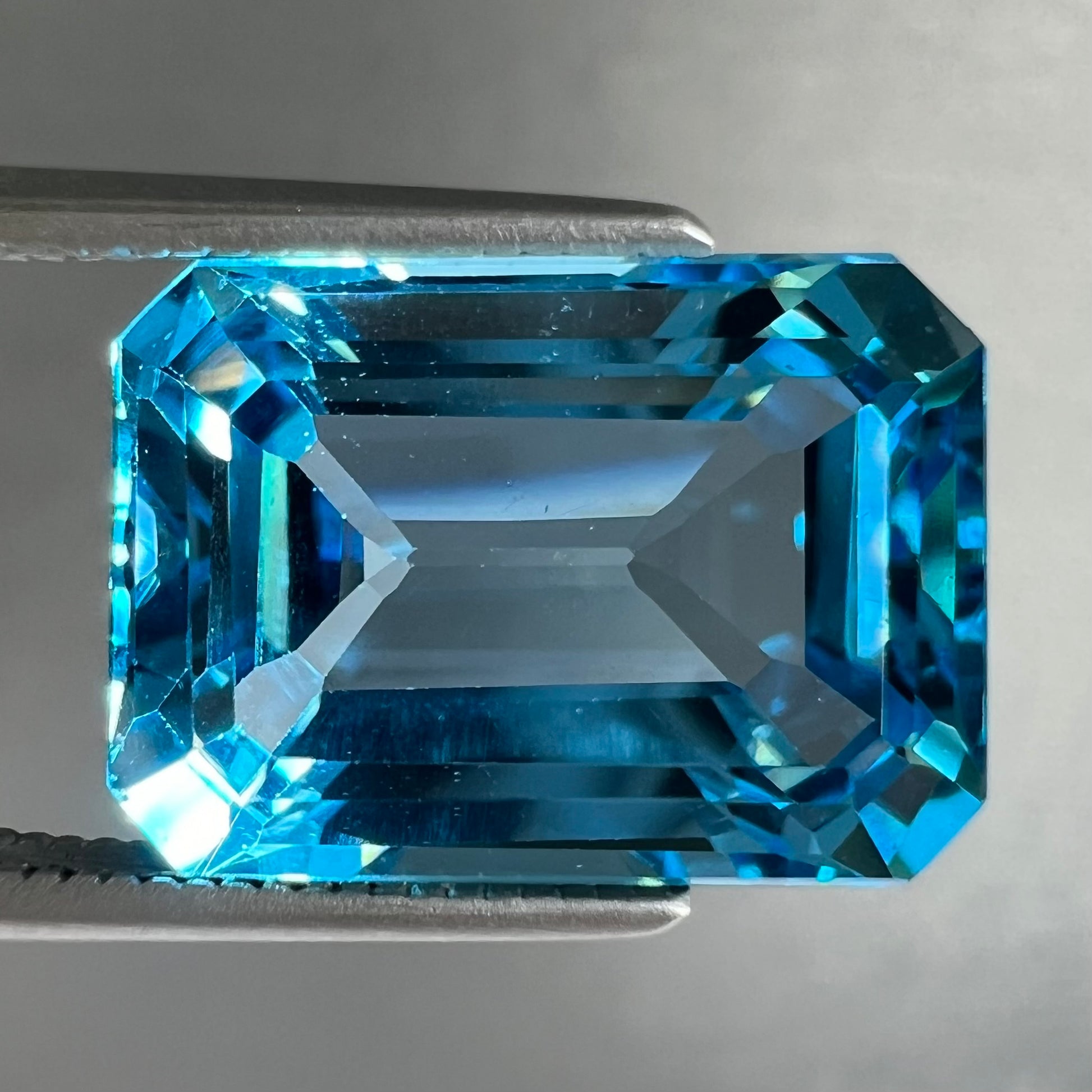An emerald cut Swiss blue topaz gemstone.  The stone is an electric blue color.