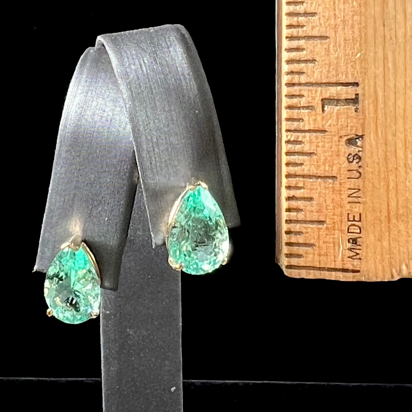 A pair of yellow gold stud earrings set with natural, pear shaped emeralds.