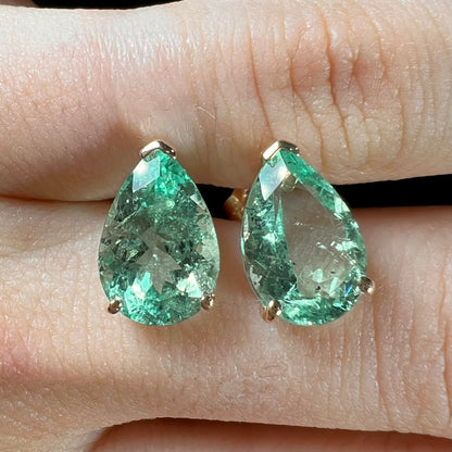 A pair of yellow gold stud earrings set with natural, pear shaped emeralds.