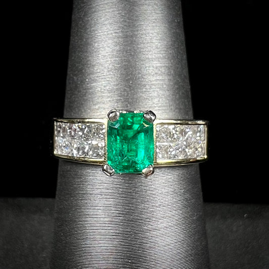 An 18 karat yellow gold ladies' emerald ring, channel set with princess cut diamonds.