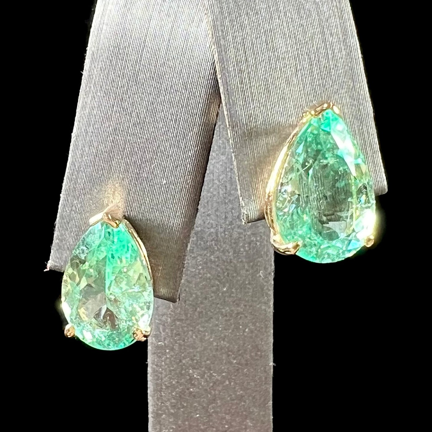 A pair of yellow gold stud earrings set with natural, pear shaped emeralds.