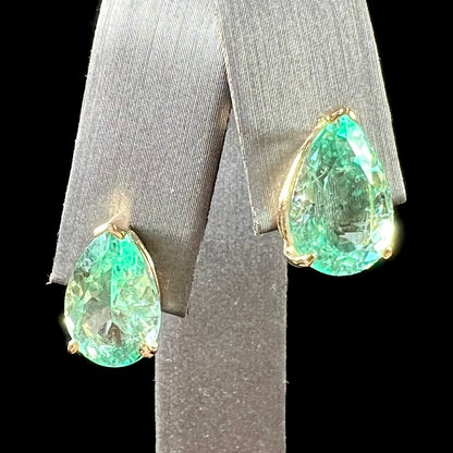 A pair of yellow gold stud earrings set with natural, pear shaped emeralds.