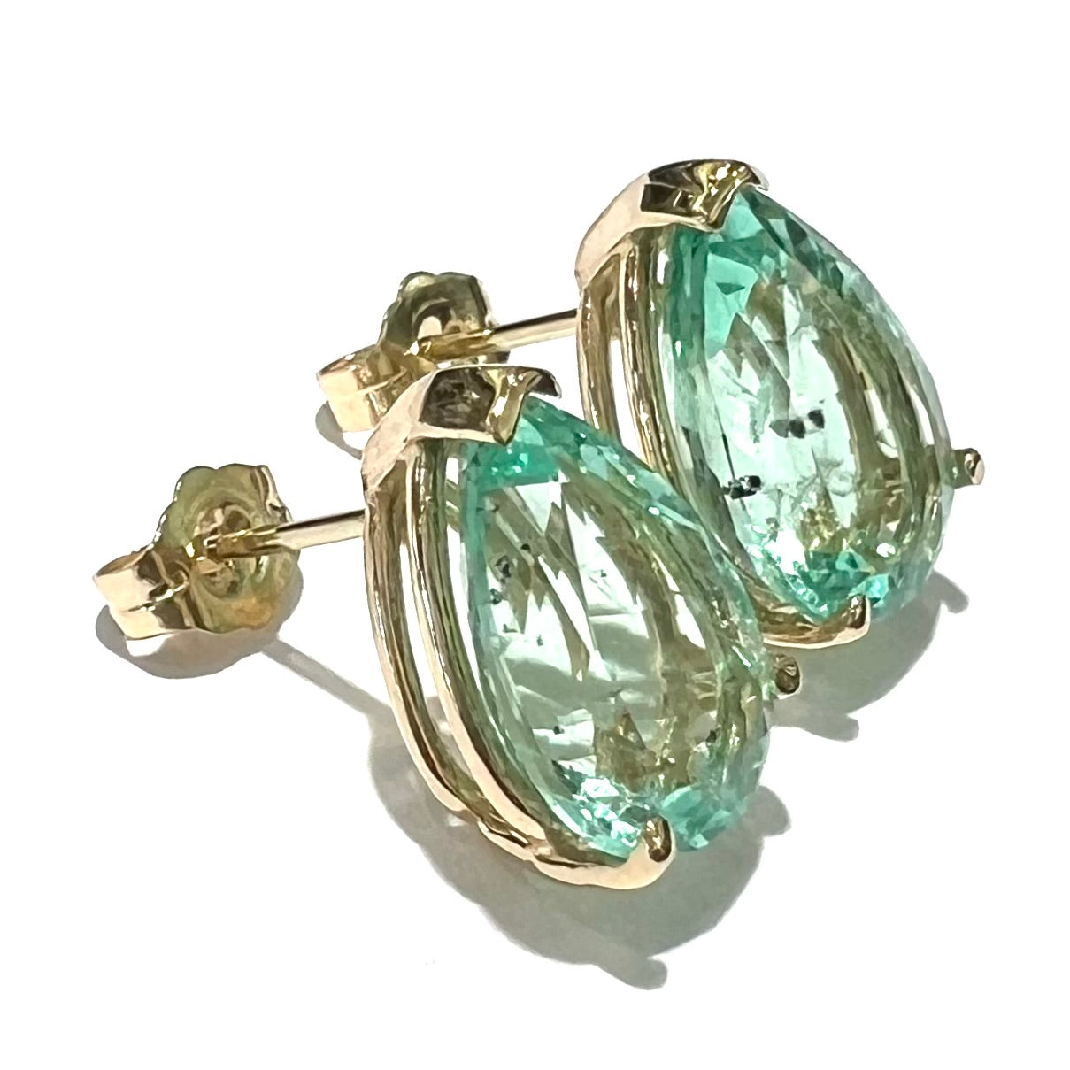 A pair of yellow gold stud earrings set with natural, pear shaped emeralds.