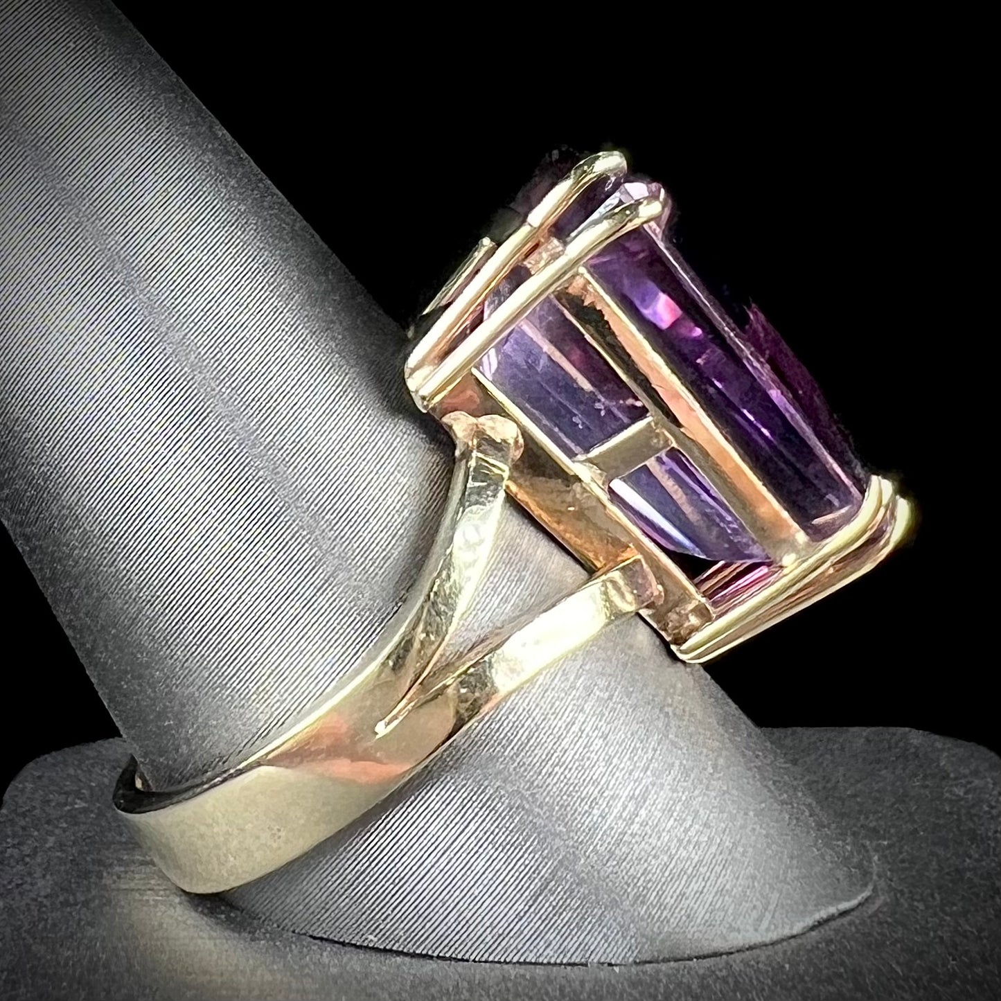 A ladies' yellow gold cocktail ring set with a shield cut purple amethyst gemstone.