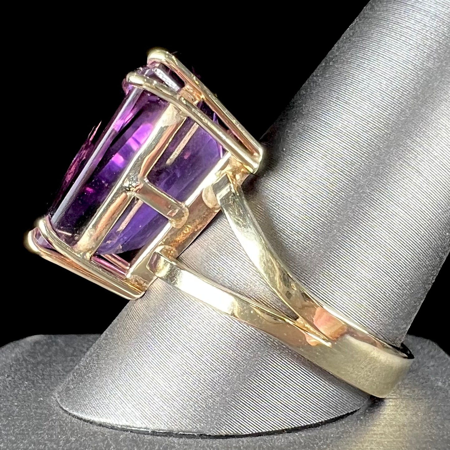 A ladies' yellow gold cocktail ring set with a shield cut purple amethyst gemstone.