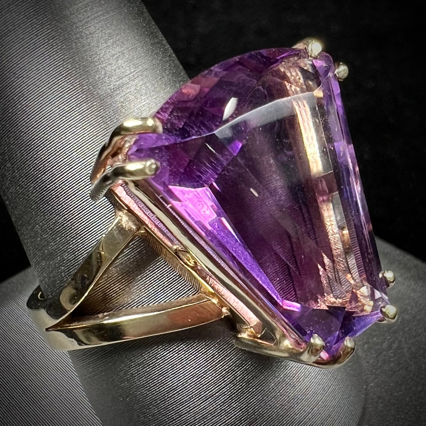 A ladies' yellow gold cocktail ring set with a shield cut purple amethyst gemstone.