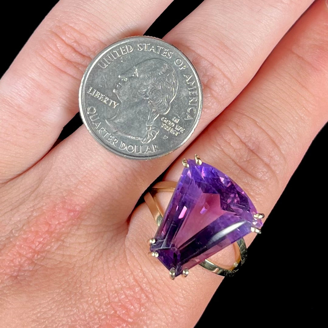 A ladies' yellow gold cocktail ring set with a shield cut purple amethyst gemstone.