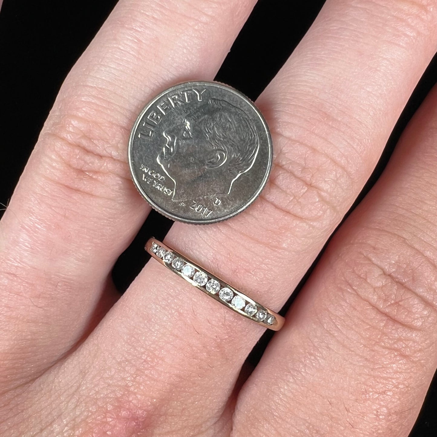 A unisex, thin yellow gold wedding band channel set with 12 round cut diamonds.