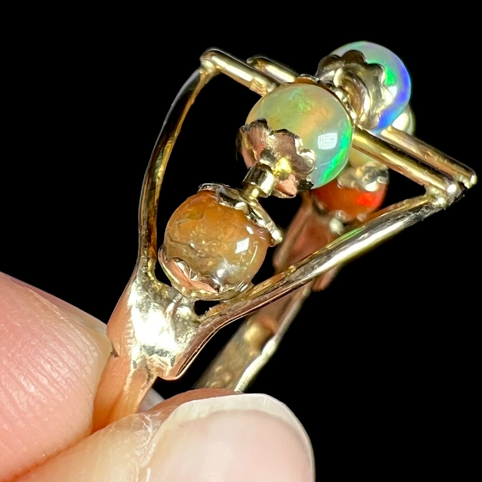 An 18 karat yellow gold ring set with five natural fire opal beads that spin along the ring.