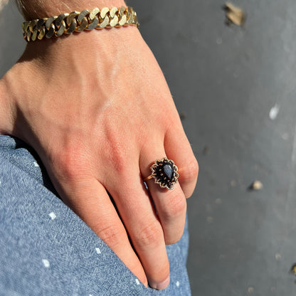 A vintage, 1940's style yellow gold ring set with a pear shaped almandine garnet.  A halo of round garnets surround the center stone.