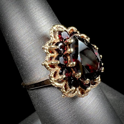 A vintage, 1940's style yellow gold ring set with a pear shaped almandine garnet.  A halo of round garnets surround the center stone.