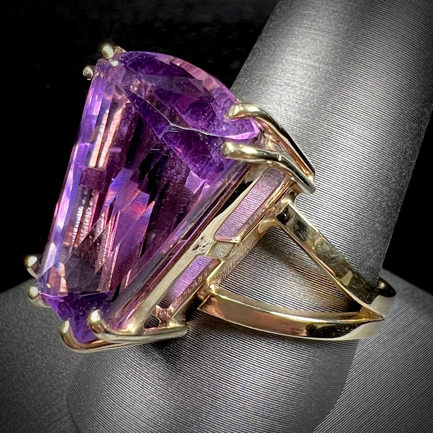 A ladies' yellow gold cocktail ring set with a shield cut purple amethyst gemstone.