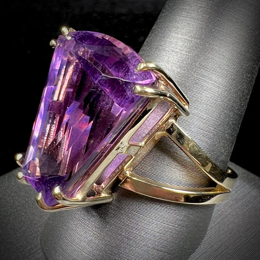 A ladies' yellow gold cocktail ring set with a shield cut purple amethyst gemstone.