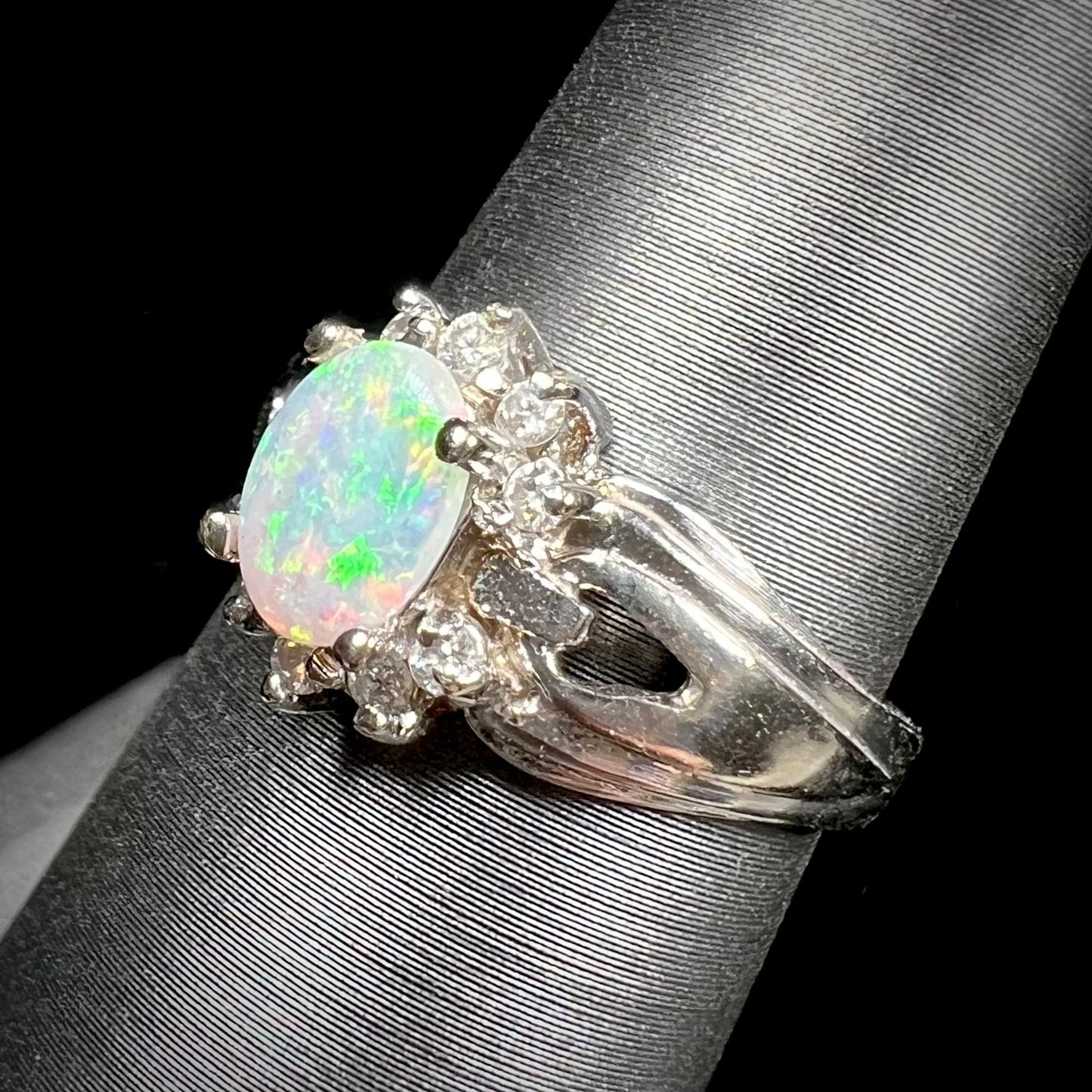 A ladies' white gold ring set with a halo of diamonds and an oval cabochon cut Australian opal.