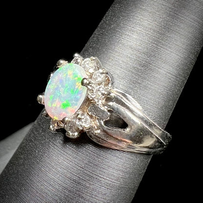 A ladies' white gold ring set with a halo of diamonds and an oval cabochon cut Australian opal.