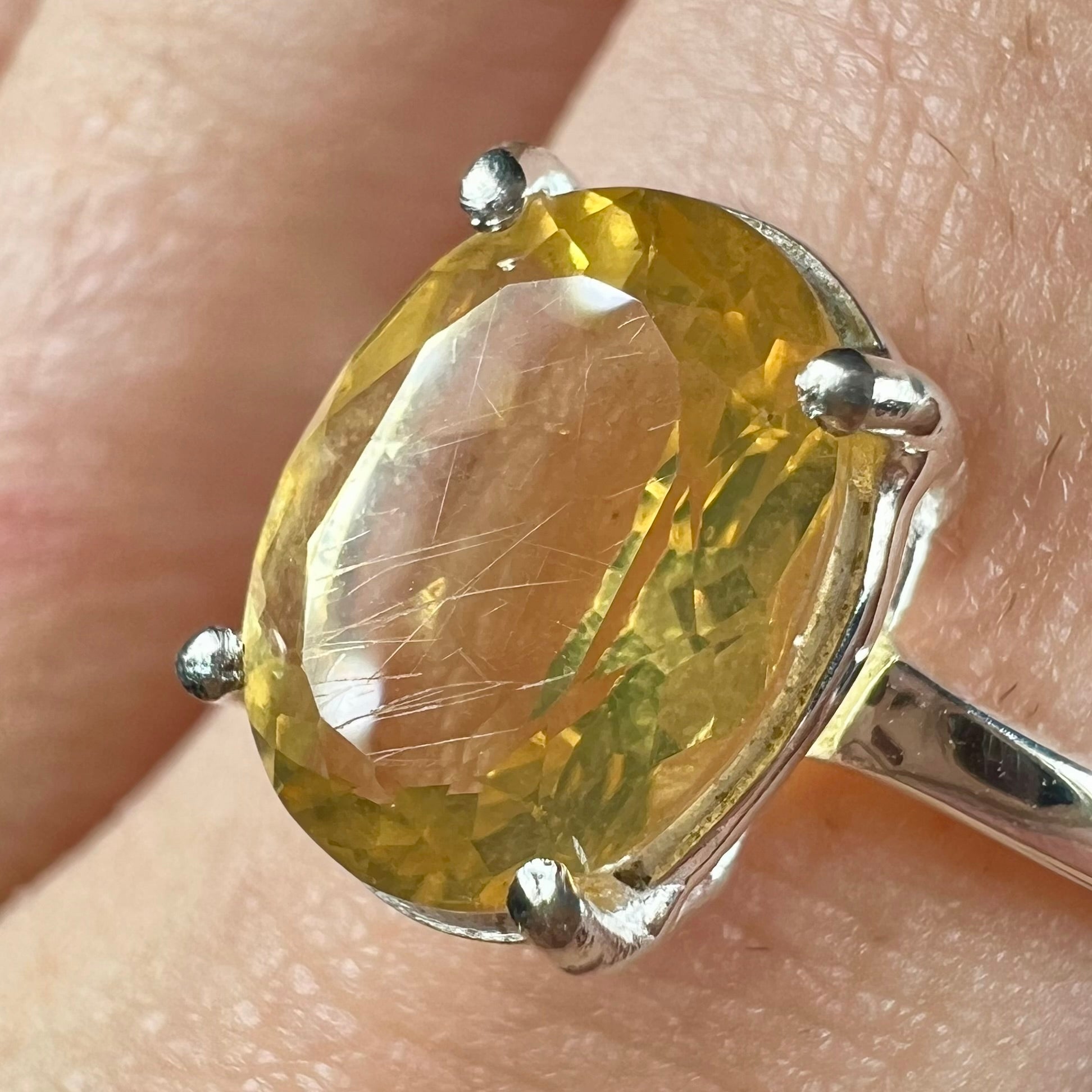 A silver solitaire ring prong-set with a natural, faceted oval cut Mexican fire opal.  The stone is a light yellow color.