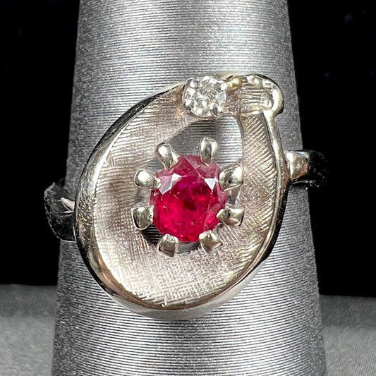 A ladies' estate white gold ruby ring set with a diamond accent stone.