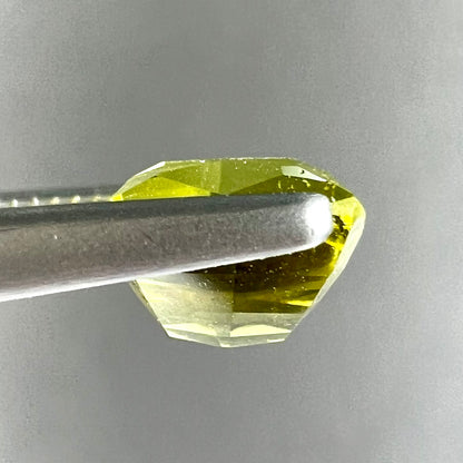 A loose, modified cushion cut greenish yellow chrysoberyl gemstone.