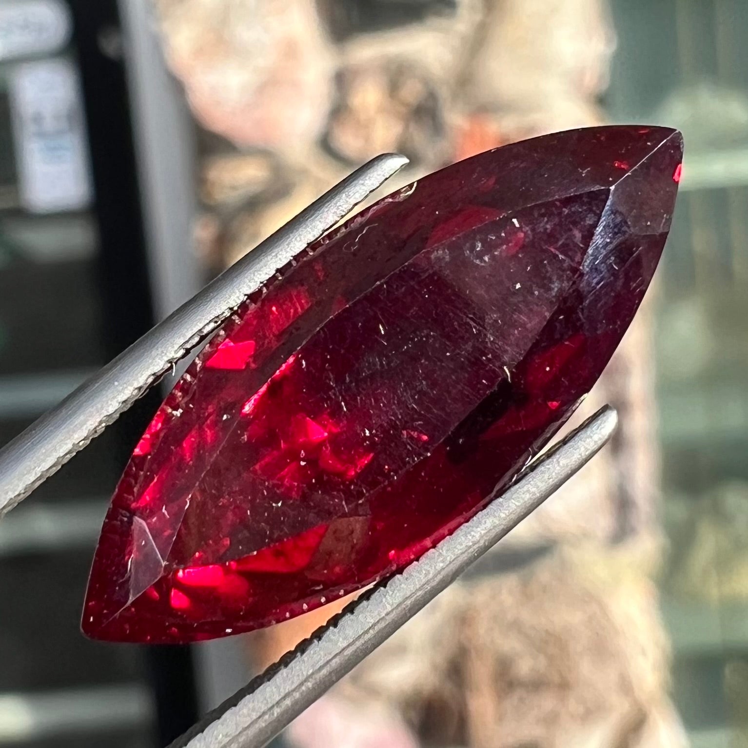 A loose, marquise cut cuprite gemstone.  The stone is a deep, crimson red color.
